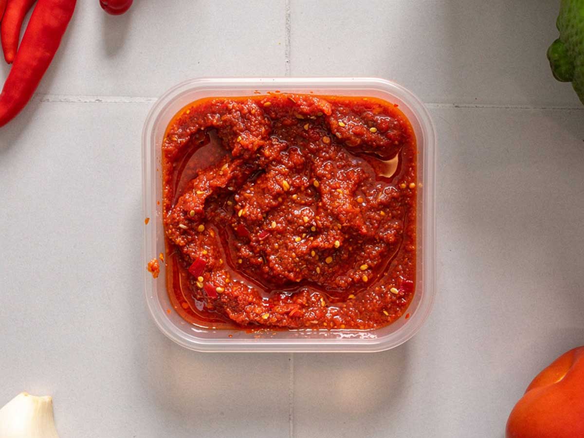 Een klein vierkant diepvriesbakjes met sambal.