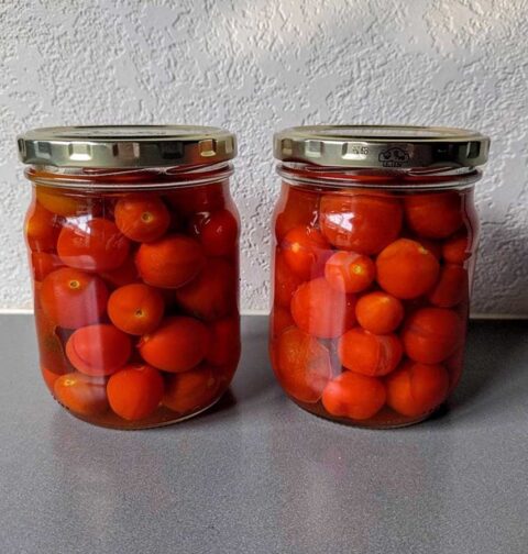 Twee inmaakpotten vol met ingemaakte hele tomaten.