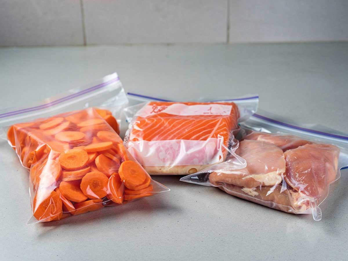 Een vacumeerzak met wortels, met zalm en met kipfilet.