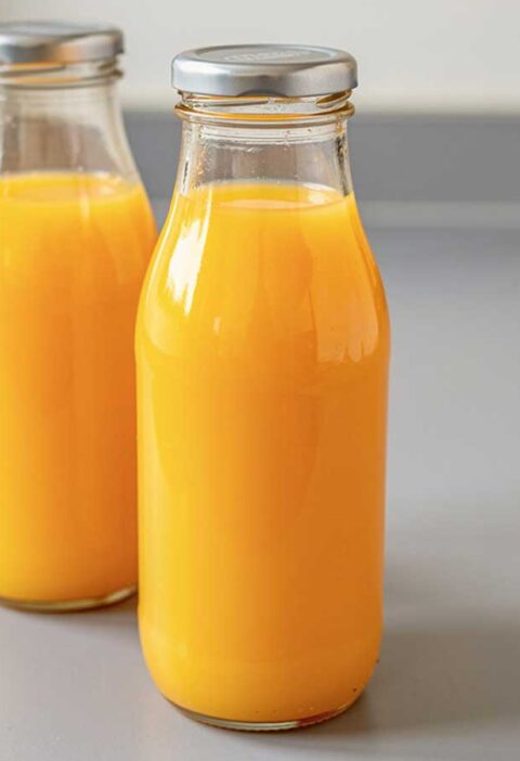 Twee afgesloten flessen met daarin zelfgemaakt Ananas-sinaasappel sap.
