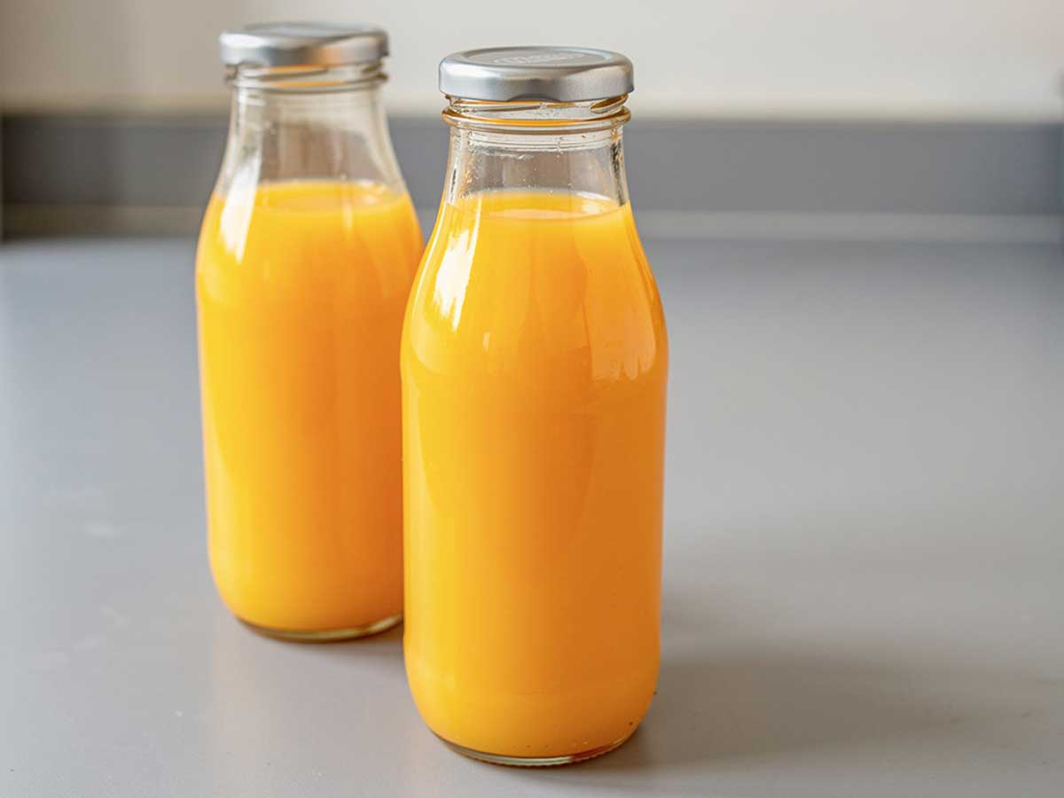 Twee afgesloten flessen met daarin zelfgemaakt Ananas-sinaasappel sap.