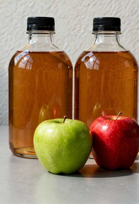 2 flessen appelciderazijn, met daarvoor 2 appels.