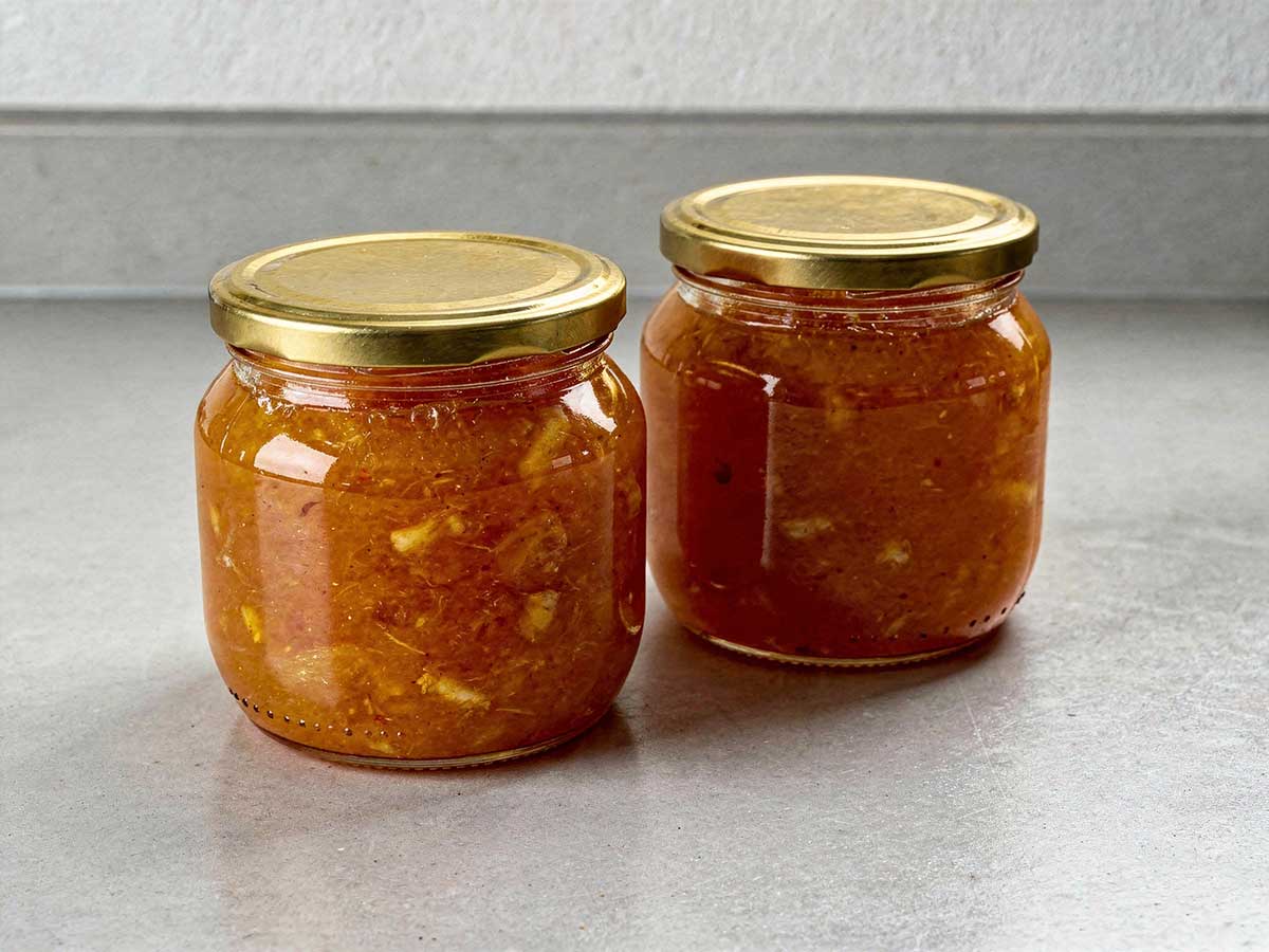 2 grote jampotten die helemaal gevuld zijn met zelfgemaakte bittere sinaasappelmarmelade.