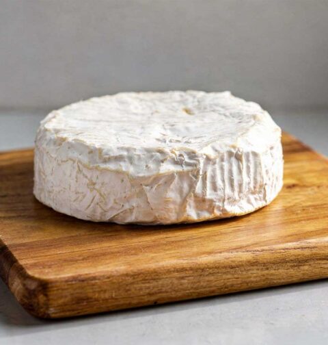 Een hele camembert op een houten snijplank.