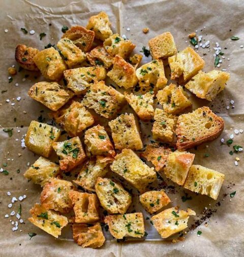 Een stuk bakpapüier waarop zelfgemaakte croutons liggen.