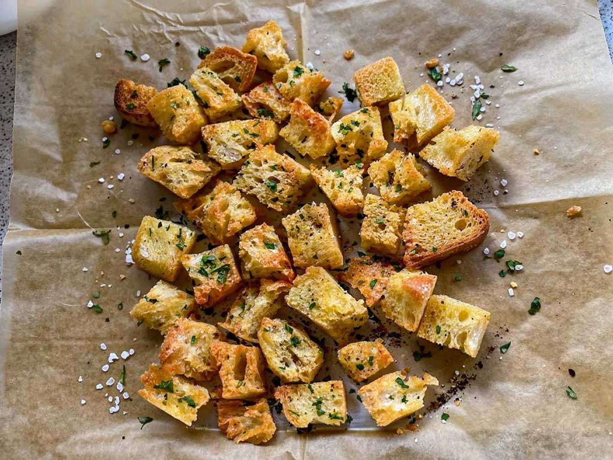 Een stuk bakpapüier waarop zelfgemaakte croutons liggen.