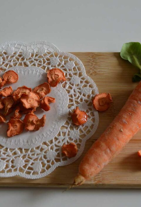 Gedroogde plakjes wortel en een hele winterpeen op een houten snijplank.
