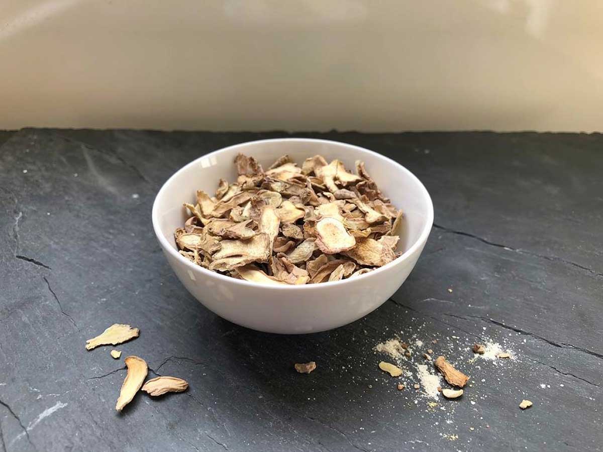 Een wit schaaltje met daarin gedroogde plakjes en stukjes gember.