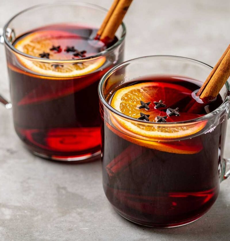 2 glazen met daarin glühwein met kaneel, citroen en meer.