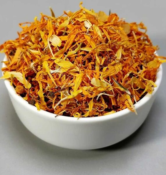 Een wit schaaltje met daarin gedroogde blomeblaadjes van goudsbloemen.