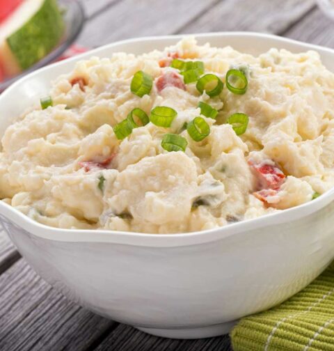Een witte schaal met net gemaakte aardappelsalade om te bewaren.