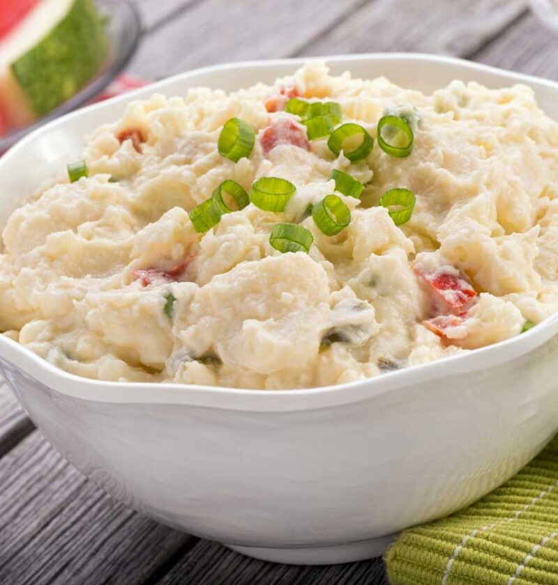 Een witte schaal met net gemaakte aardappelsalade om te bewaren.
