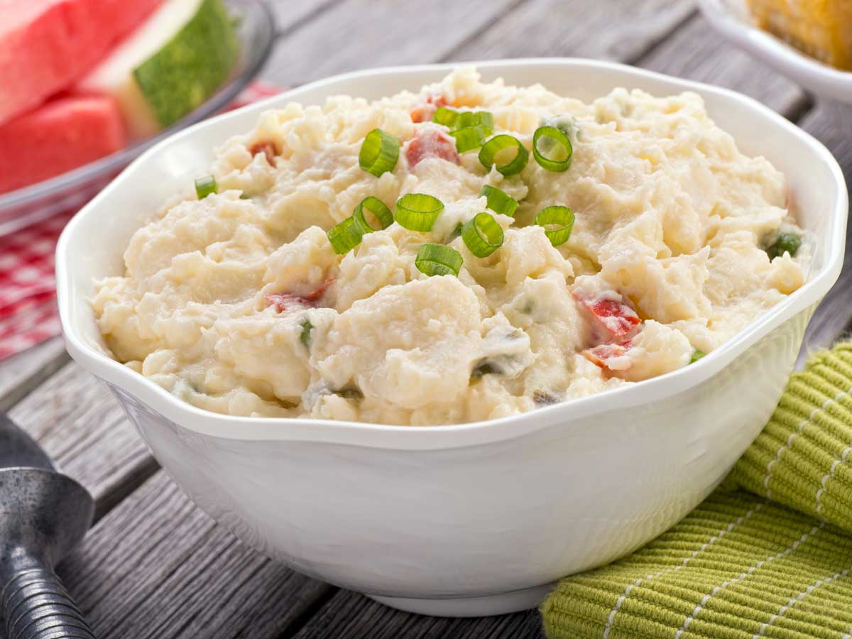 Een witte schaal met net gemaakte aardappelsalade om te bewaren.