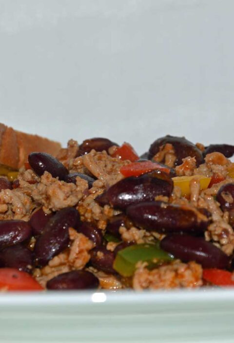 Een bord met chili con carne met 2 boterhammen.