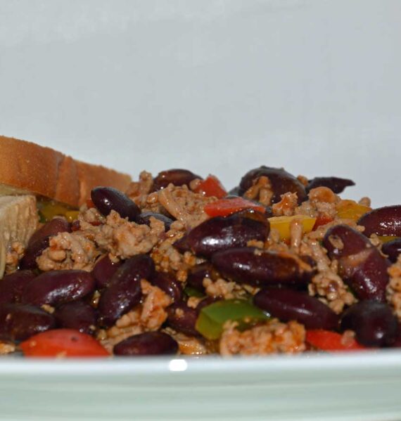 Een bord met chili con carne met 2 boterhammen.