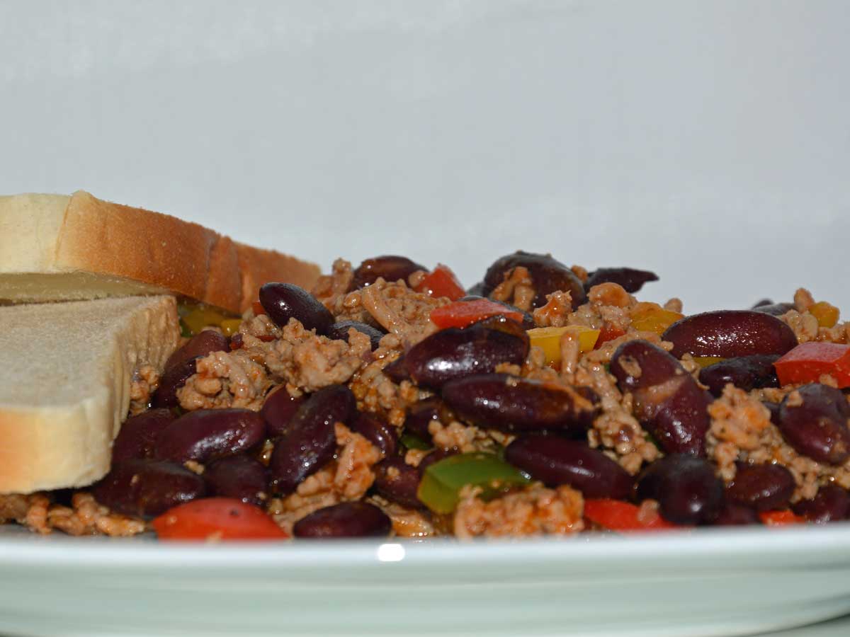 Een bord met chili con carne met 2 boterhammen.