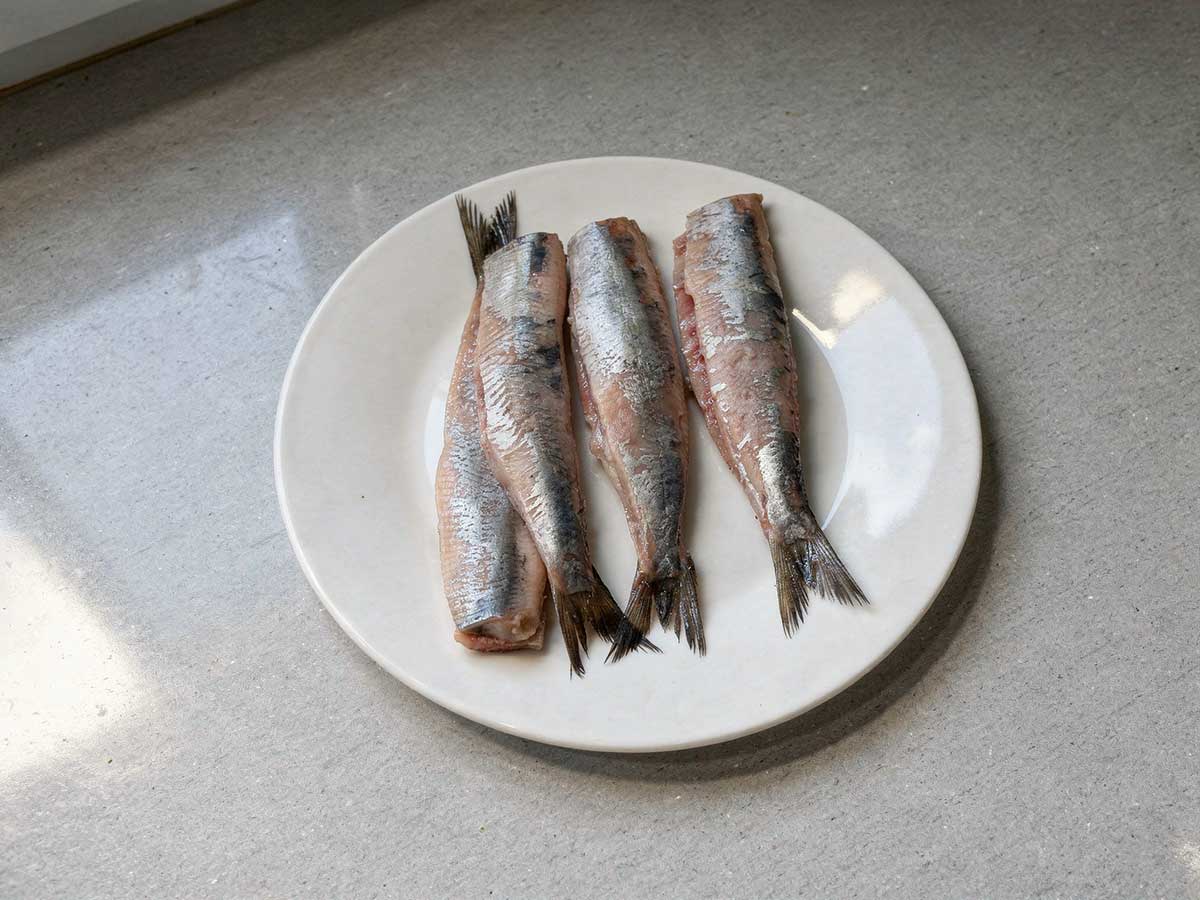 4 schoongemaakte haringen op een wit bord.