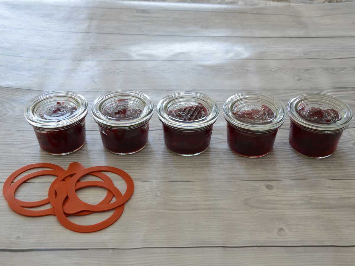 5 inmaakpotten gevulde met kersen, klaar om in te maken.