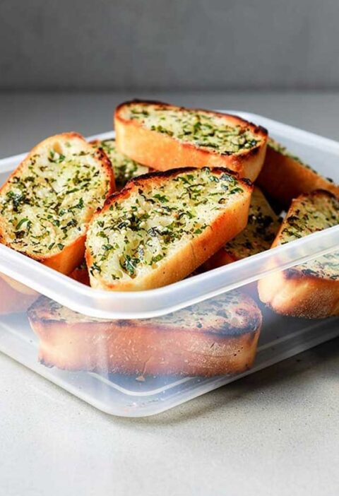 Een plastic bakje met daarin verschillende plakken zelfgemaakt en gedroogd knoflookbrood.