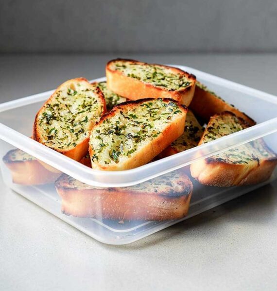 Een plastic bakje met daarin verschillende plakken zelfgemaakt en gedroogd knoflookbrood.