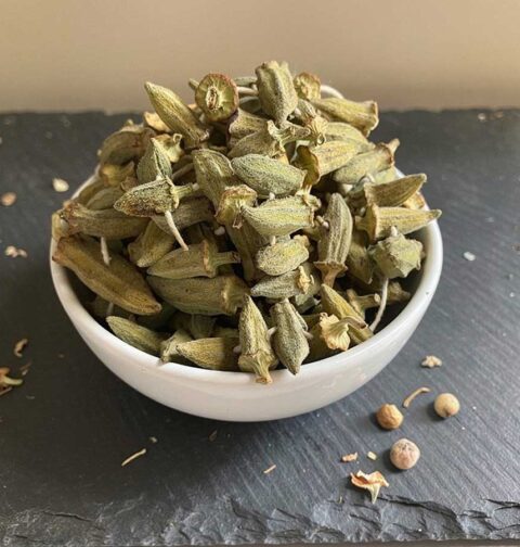Een wit schaaltje gevuld emt gedroogde, hele okra.