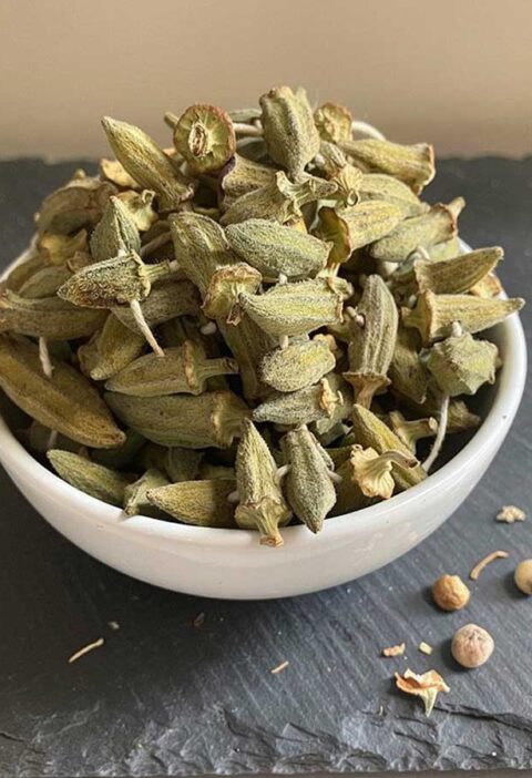 Een wit schaaltje gevuld emt gedroogde, hele okra.