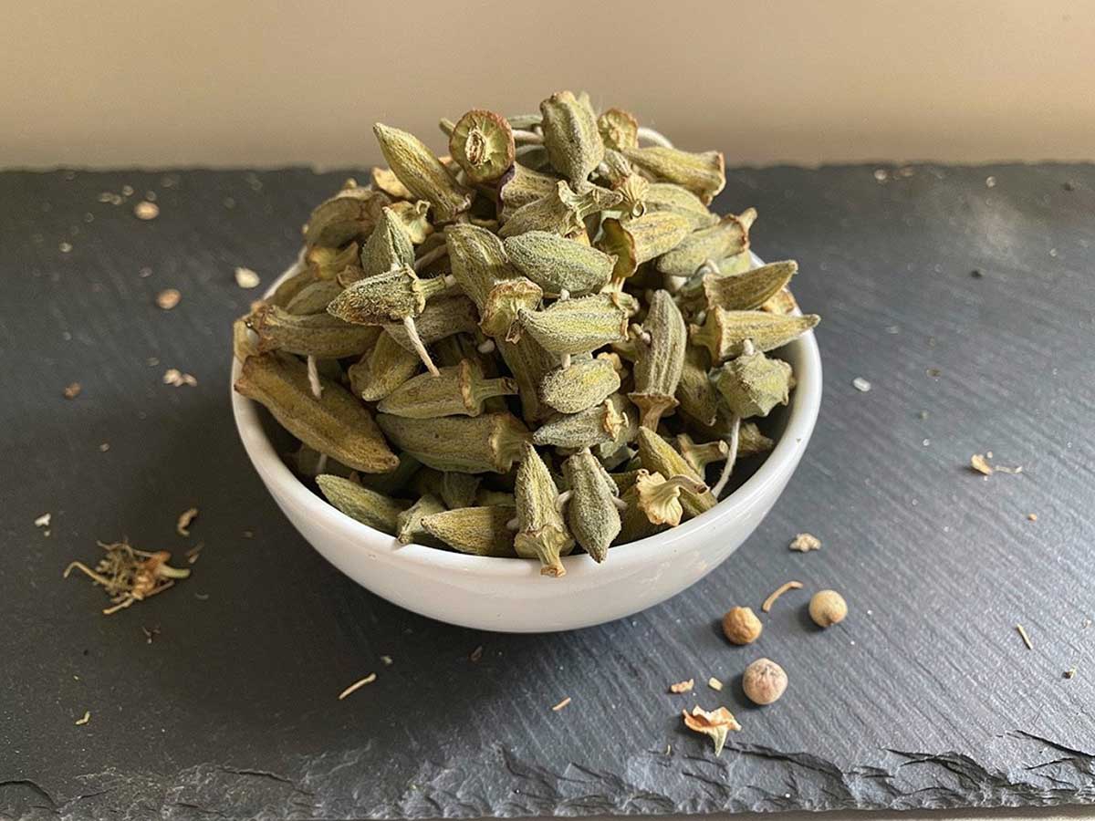 Een wit schaaltje gevuld emt gedroogde, hele okra.