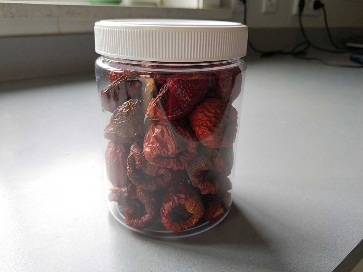 Een voorraadbus vol met gedroogde hele paprika, zonder stelen, zaad of zaadlijsten.