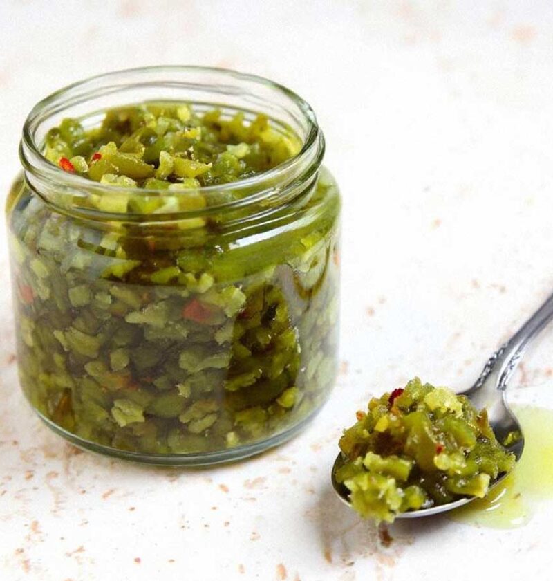 Een glazen potje met pikante sweet pickle relish, en daarnaast een lepel met inhoud.