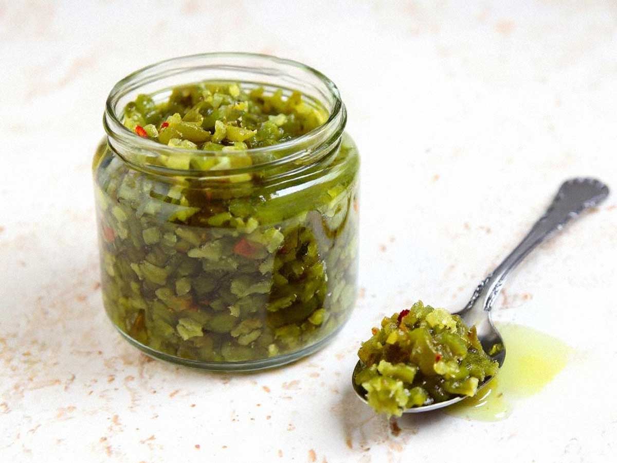 Een glazen potje met pikante sweet pickle relish, en daarnaast een lepel met inhoud.