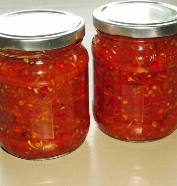 Twee grote potten met daarin zelfgemaakte rode peperjam, met pitjes.