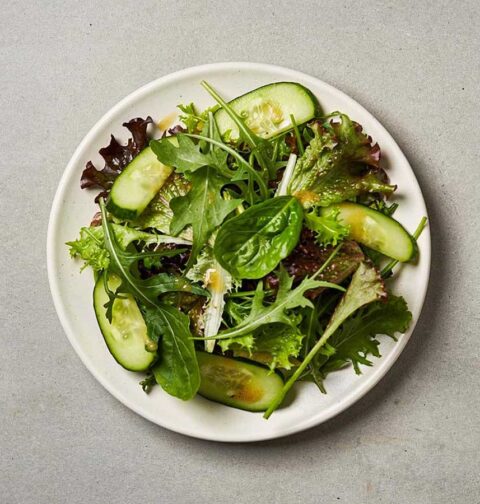 Een wit bord met daarop een groene salade.