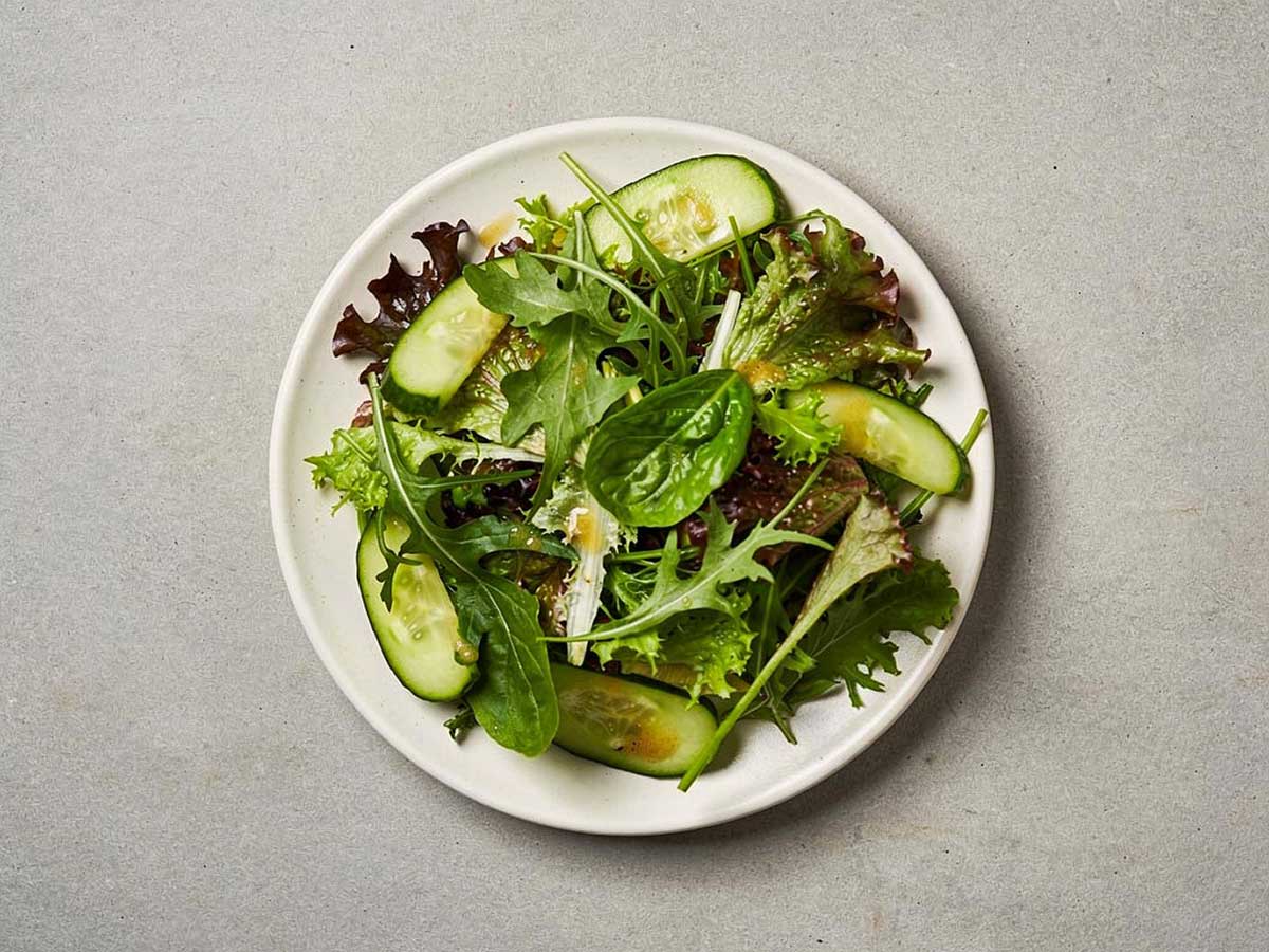 Een wit bord met daarop een groene salade.