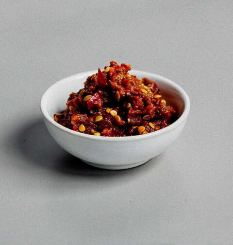 Een klein wit schaaltje met zelfgemaakte sambal oelek.