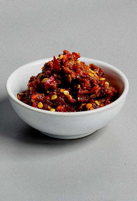 Een klein wit schaaltje met zelfgemaakte sambal oelek.