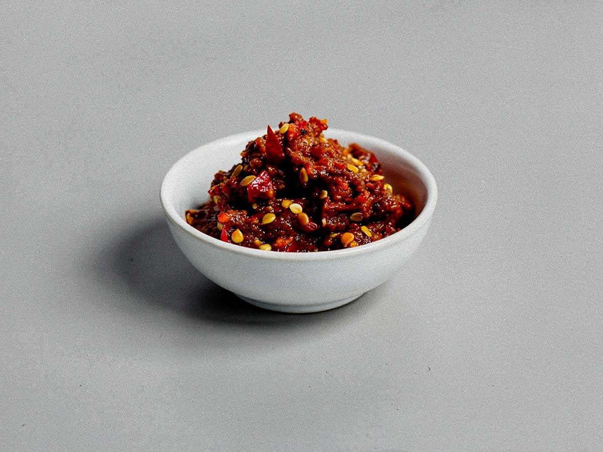 Een klein wit schaaltje met zelfgemaakte sambal oelek.