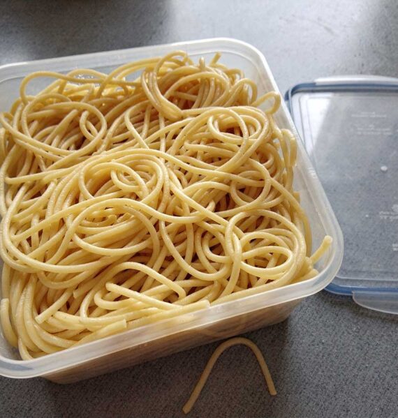Een diepvriesbak vol met gekookte spaghetti.