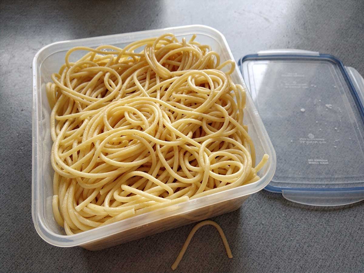Een diepvriesbak vol met gekookte spaghetti.