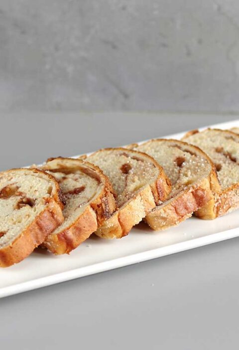 6 sneden suikerbrood op een witte platte schaal.