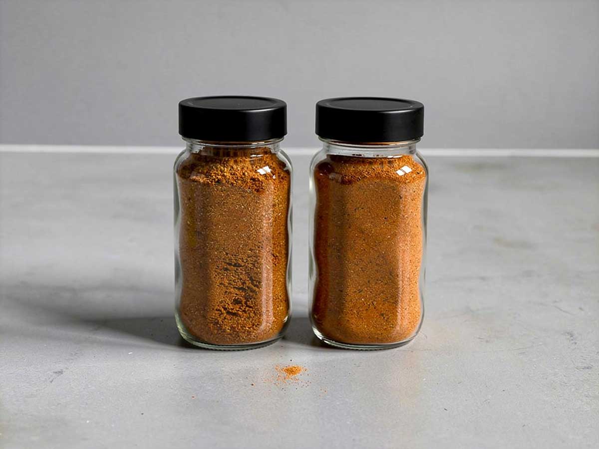 Twee kruidenpotjes die helemaal gevuld zijn met tandoorie kruiden.