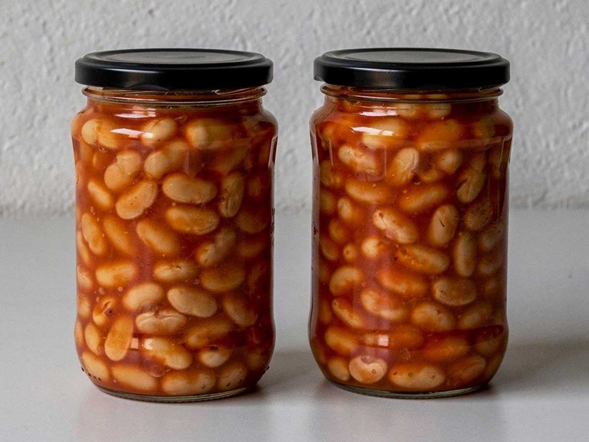 Twee grote potten geweckte witte bonen in tomatensaus.