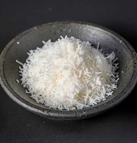 Een donker schaaltje met sliertjes gedroogde kokos.