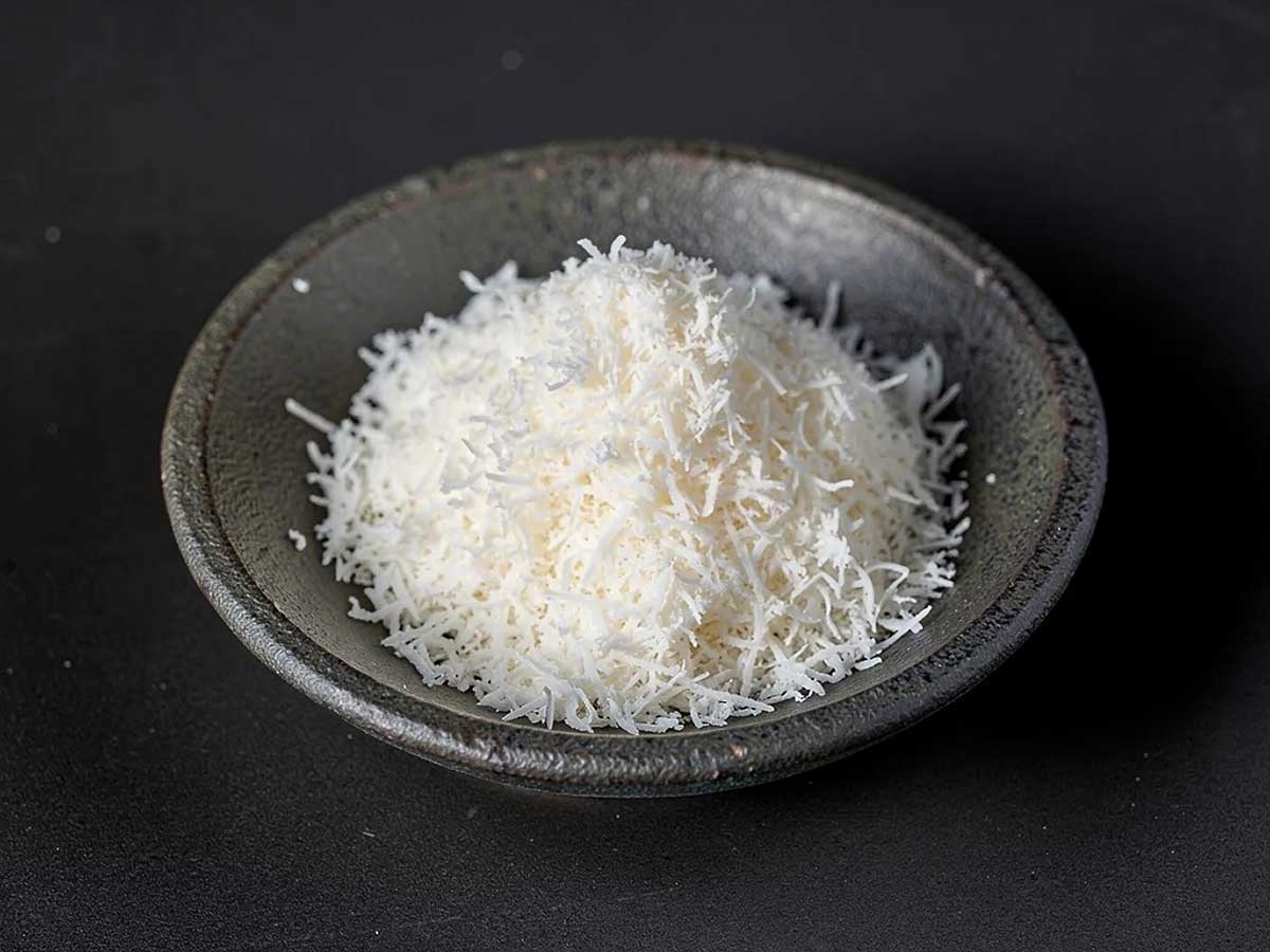 Een donker schaaltje met sliertjes gedroogde kokos.