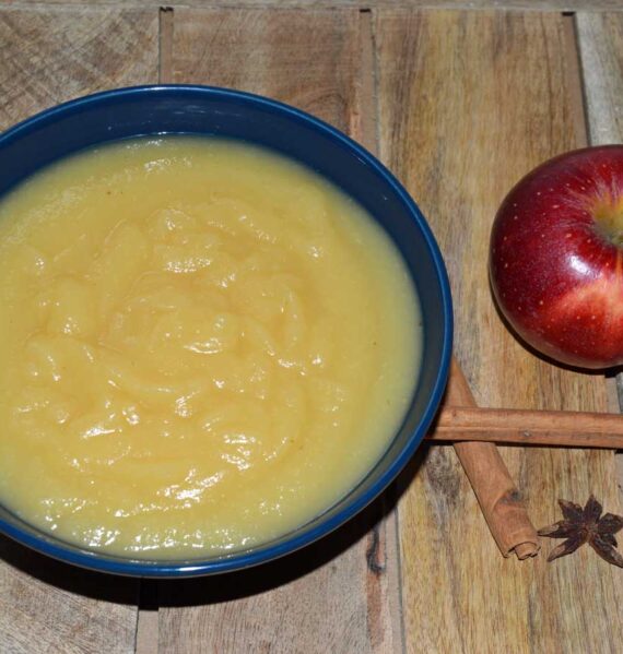 Schaaltje zelfgemaakte appelmoes met daarnaast kaneelstok en appel, klaar om te wecken.