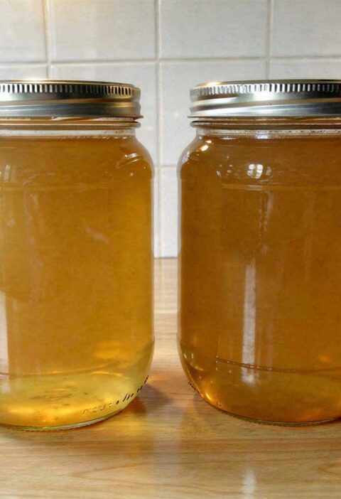 Twee grote glazen weckpotten met schroefdeksel gevuld met verse, heldere bouillon.