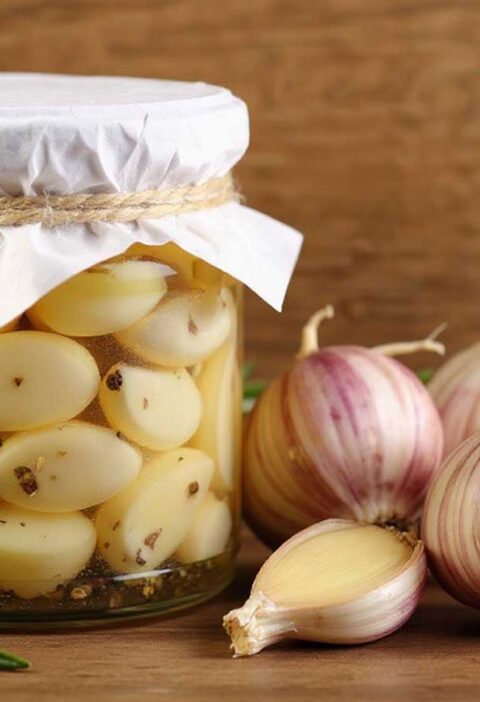 1 potje ingemaakte knoflook, naast verse knoflook.