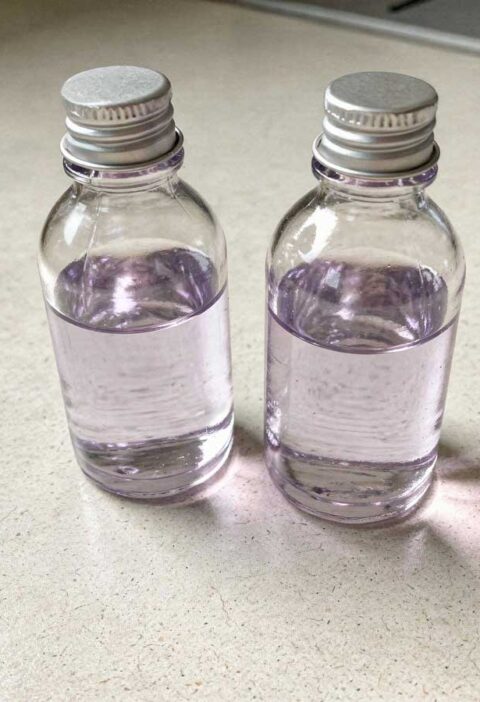 Twee glazen flesjes met zelfgemaakte lavendelolie op het aanrecht.