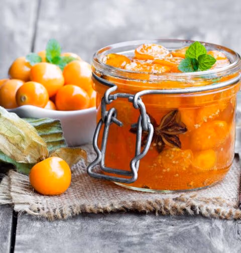 Physalis chutney in een open weckpot, met kaapse bessen ernaast.
