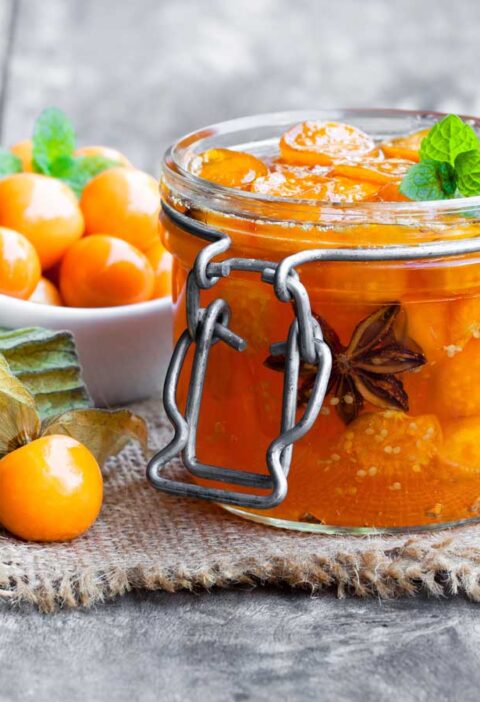 Physalis chutney in een open weckpot, met kaapse bessen ernaast.